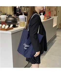 Détail du sac cabas en toile bleu marine avec imprimé merci blanc dans un cadre décontracté