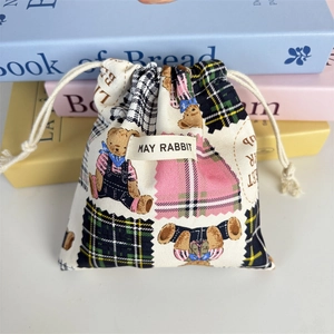 Close-up of beige canvas drawstring pouch with cute bear pattern and woven label