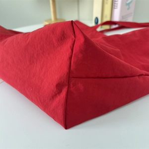 Detailed close-up showing the durable red nylon fabric and reinforced bottom of the tote