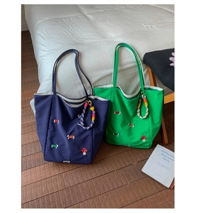 Close-up of navy and green canvas tote bags with mushroom embroidery and woven handles
