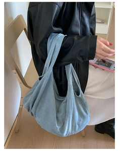Close-up of a slouchy light blue suede hobo tote bag showing soft texture and drape