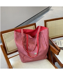 Detail of red and white checkered canvas tote bag with red handles on a wooden chair