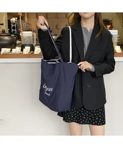 Détail du cabas en toile bleu marine avec texte 'beyou merci' et anses tressées