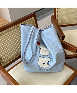 Detail of light blue canvas tote with cute bear embroidery and blue plaid handles