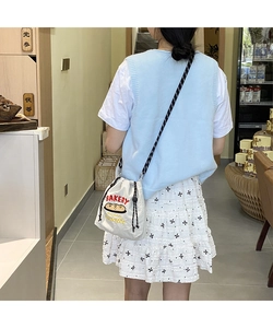 Detail of cream drawstring canvas bag with bakery embroidery shown on a model