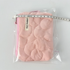 Vue détaillée de la pochette matelassée mesurant environ 11,5 cm avec un mètre ruban
