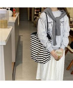 Détail du sac cabas en toile à rayures noires et blanches avec plaque logo dorée