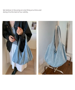 Detail of light blue suede tote bag showing hobo style and soft texture on a metal stand