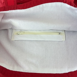 Detail view of red nylon tote bag featuring white canvas lining and internal zipper pocket