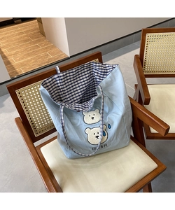 Close-up of light blue canvas tote bag with cute bear print and blue checkered lining