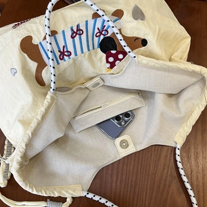 Dettaglio della borsa tote a coulisse con tasca a cerniera e chiusura a scatto magnetico