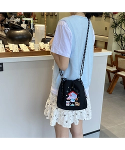 Model wearing a black canvas bucket bag with cute cartoon embroidery in a cafe