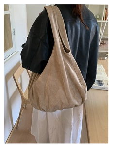 Detail of a large beige suede tote bag showing soft texture and slouchy design on shoulder
