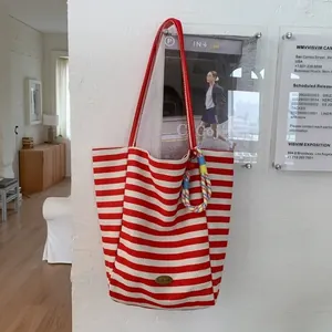 Canvas tote bag with red stripes, handmade label and braided ornament hanging on a wall