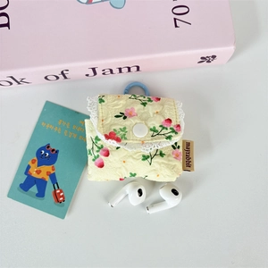 Detail of yellow floral quilted earphone case with white lace trim and metal carabiner