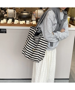 Détail du sac cabas en toile à rayures noires et blanches avec plaque logo en métal
