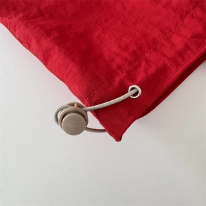 Detail of red nylon fabric with grey drawstring and adjustable spring toggle buckle