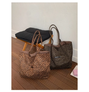 Detail of leopard print tote bags in light and dark brown with branded leather labels