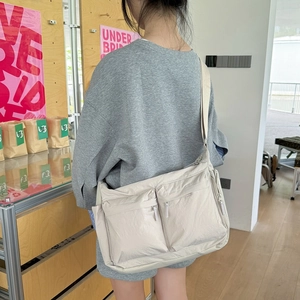 Détail du sac bandoulière en nylon beige avec poches zippées et large bandoulière