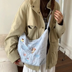 Detail of light blue heart-quilted tote bag with puppy and pudding cartoon embroidery