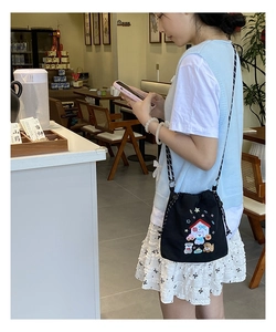 Detail of black canvas drawstring bag with colorful animal embroidery and woven strap