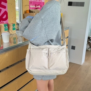 Détail du sac bandoulière en nylon beige avec deux poches zippées et sangle large