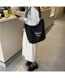 Détail du sac cabas en toile noire avec texte merci blanc et bandoulière robuste