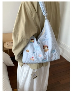 Detail of light blue quilted tote bag featuring cute cartoon puppy embroidery and soft texture