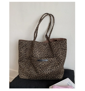 Detailed view of leopard print tote bag with long straps and black leather brand tag