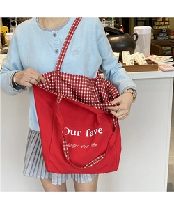 Detail of red canvas tote bag with red and white checkered lining and inner strap detail