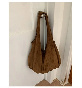 Detail of dark brown suede hobo bag texture hanging on door handle for daily casual use