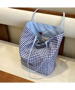 Close-up of blue and white checkered tote bag with cute bear embroidery and metal logo