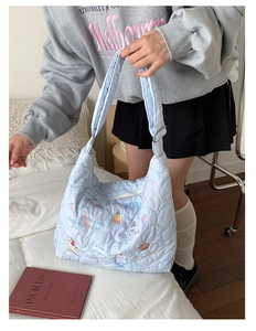Detail of light blue heart-quilted tote bag featuring colorful cat and dessert embroidery