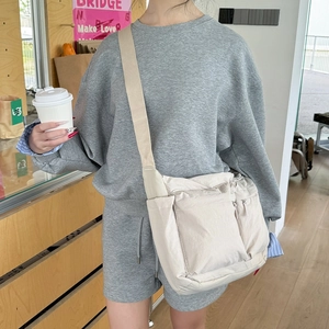 Détail du sac bandoulière en nylon beige avec poches zippées et sangle ajustable