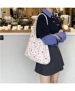 Detail of white quilted tote bag featuring red cartoon patterns and wide shoulder straps