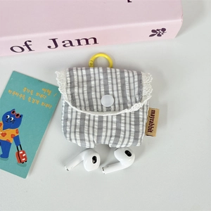 Detail of grey striped fabric earphone case with white lace trim and yellow hook