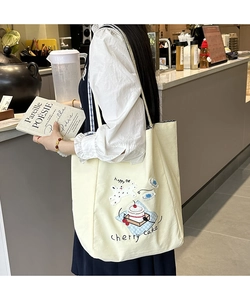 Detail of cream canvas tote bag with 3D embroidery of cherry cake and Happy Day text