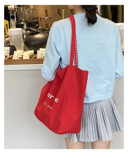 Close-up of red canvas tote bag with white lettering and red checkered lining detail