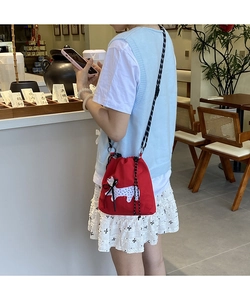 Detail of red drawstring canvas shoulder bag with puppy print and black bow detail