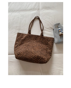 Flat lay of leopard print canvas tote bag with reinforced handles on white fabric