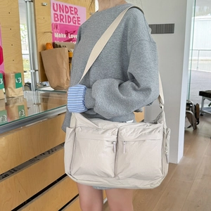 Sac bandoulière en nylon beige à poches multiples porté par un mannequin