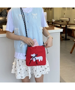 Detail of red drawstring canvas crossbody bag with cute puppy patch and black ribbon