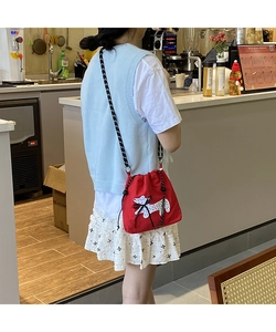 Detail of red drawstring canvas bag with dog patch and checkered strap in cafe setting