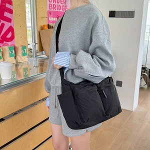 Détail d'un sac bandoulière noir en nylon avec multiples poches et sangle réglable robuste