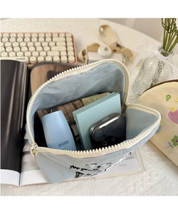 Beauty case blu in nylon con ricamo su tavolo in pizzo con oggetti di scena lifestyle