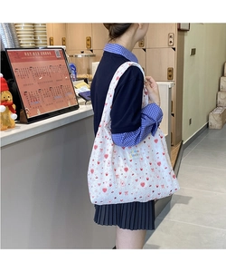 Close-up of quilted white canvas tote bag with red heart, strawberry, and bow prints