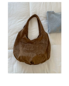 Detailed close-up of brown suede hobo bag texture on white fabric background