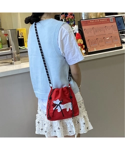 Detail of red drawstring bucket bag with dog print and textured black and white woven strap
