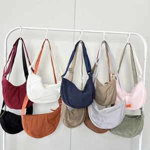 Detailed close-up of corduroy crescent bags in multiple colors hanging on a white rack
