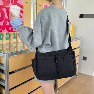 Sac messager noir en nylon avec plusieurs poches et bandoulière réglable sur modèle